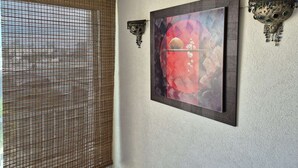 A room with a wall-mounted painting, a textured wall, and a window with a woven blind. - Apartment Natura Beach 203 with parking space - 4 people (AGDE)