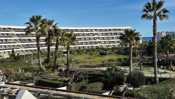 A modern building with a geometric facade, palm trees, and a clear sky. - Apartment Natura Beach 203 with parking space - 4 people (AGDE)