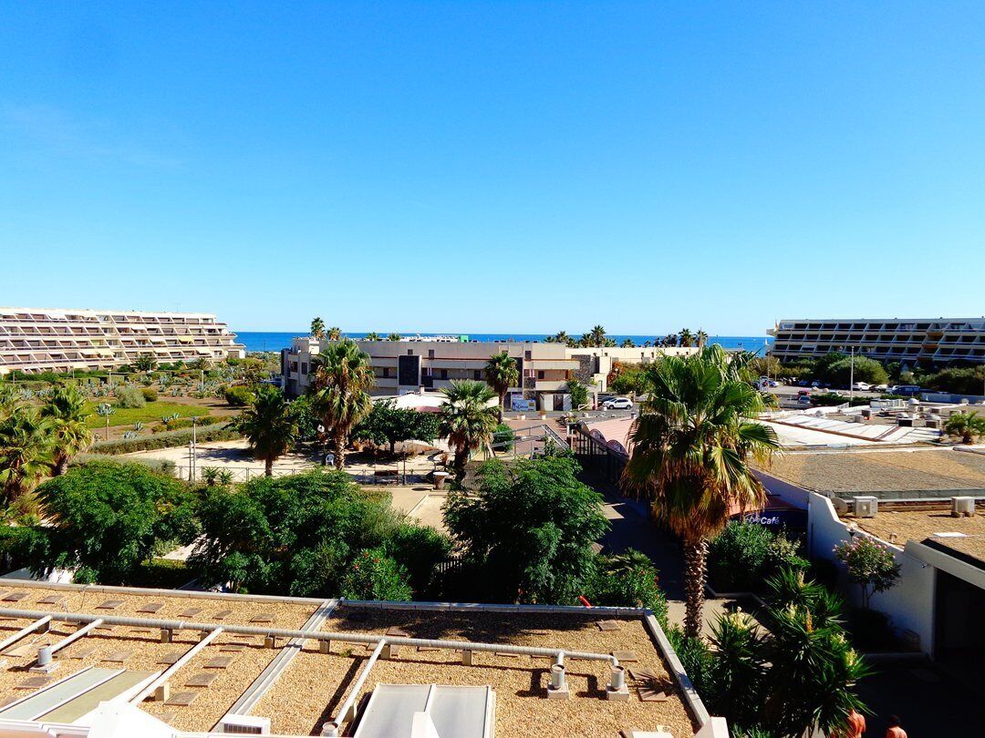 Ein Hotel mit Dachterrasse, Palmen und Blick auf das Meer.