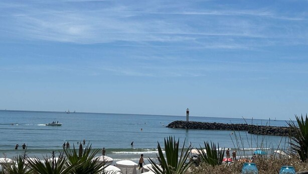 A beach with a lighthouse, calm sea, and people enjoying the water. - Natura Beach - Apartment NB303 - 8 people (AGDE)