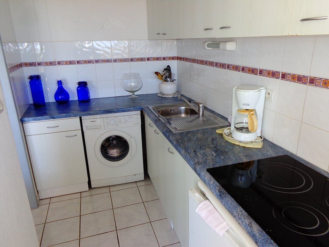 A compact kitchen with a washing machine, a coffee maker, and a sink.