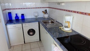 A compact kitchen with a washing machine, a coffee maker, and a sink. - Natura Beach - Apartment NB303 - 8 people (AGDE)