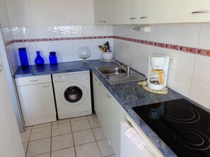 A compact kitchen with a washing machine, a coffee maker, and a sink. - Natura Beach - Apartment NB303 - 8 people (AGDE)