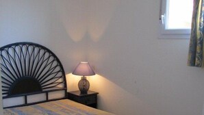 Een slaapkamer met een bed, een bedlamp, een raam met gordijnen en een radiator.