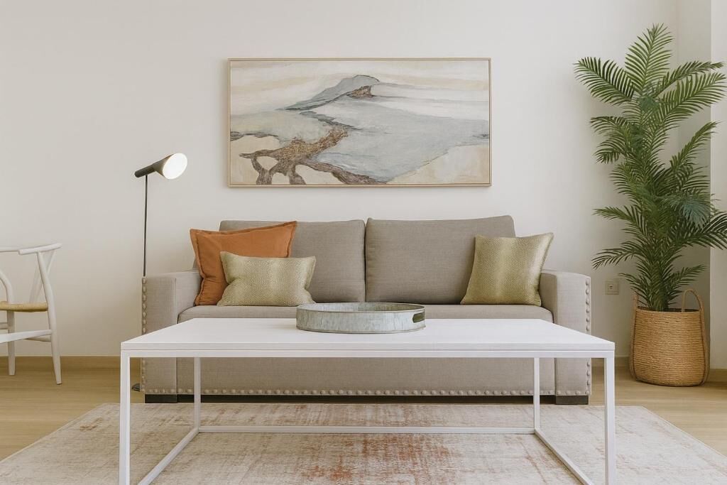 A living room with a sofa, a coffee table, a floor lamp, and a painting on the wall.