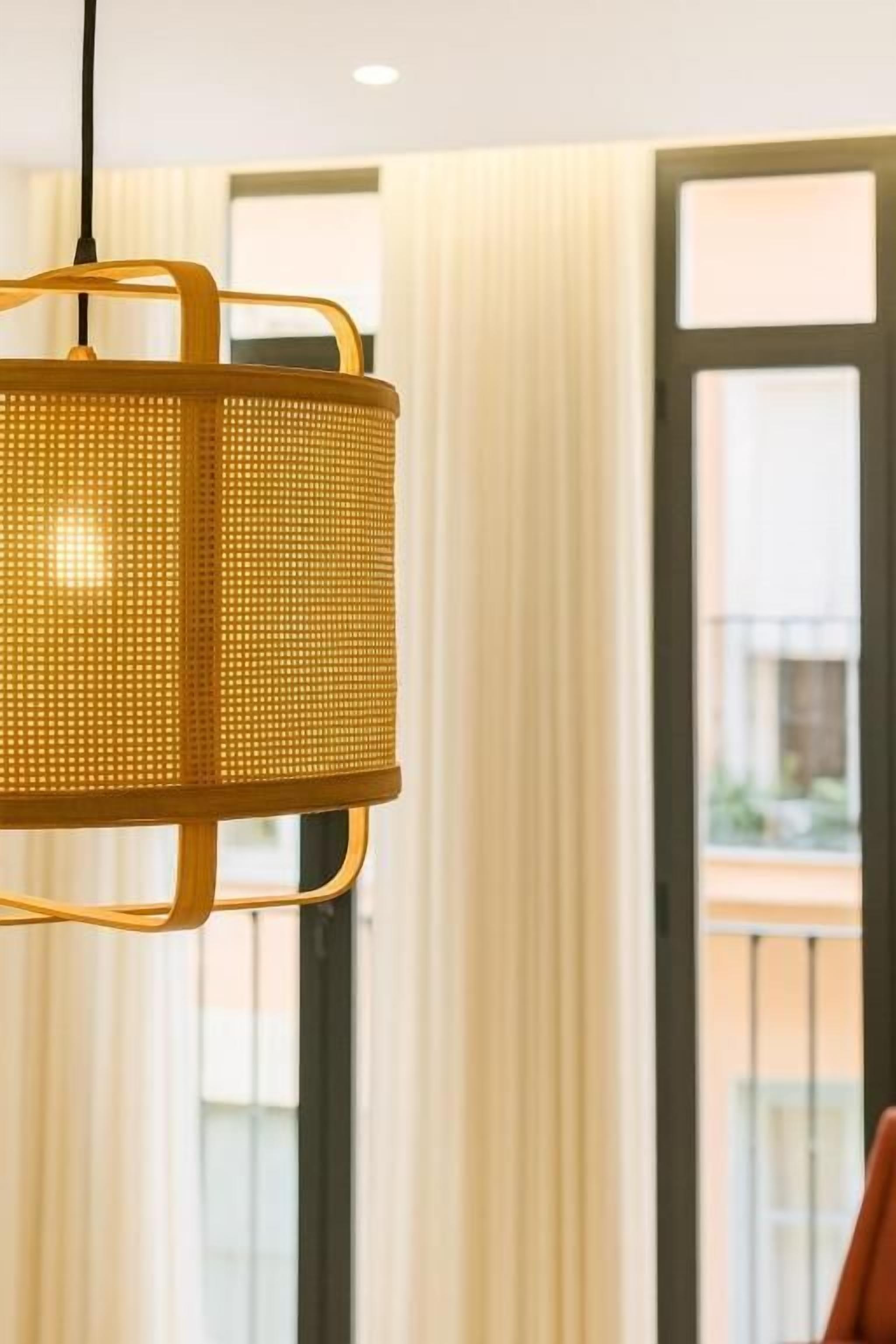 Une pièce dotée d’une grande fenêtre, d’un luminaire suspendu et offrant une vue sur l’extérieur.