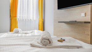 A hotel room with a bed, a TV, and a wooden headboard. - XZLLENZ Hotel (Oberasbach)