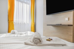 A hotel room with a bed, a TV, and a wooden headboard.