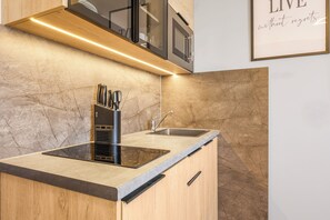 A modern kitchen with a built-in stove, a sink, and a countertop with a knife block. - XZLLENZ Hotel (Oberasbach)