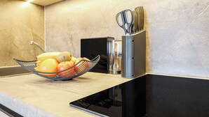 A kitchen counter with a fruit bowl containing bananas, oranges, and apples, a knife block, and a black appliance. - XZLLENZ Hotel (Oberasbach)