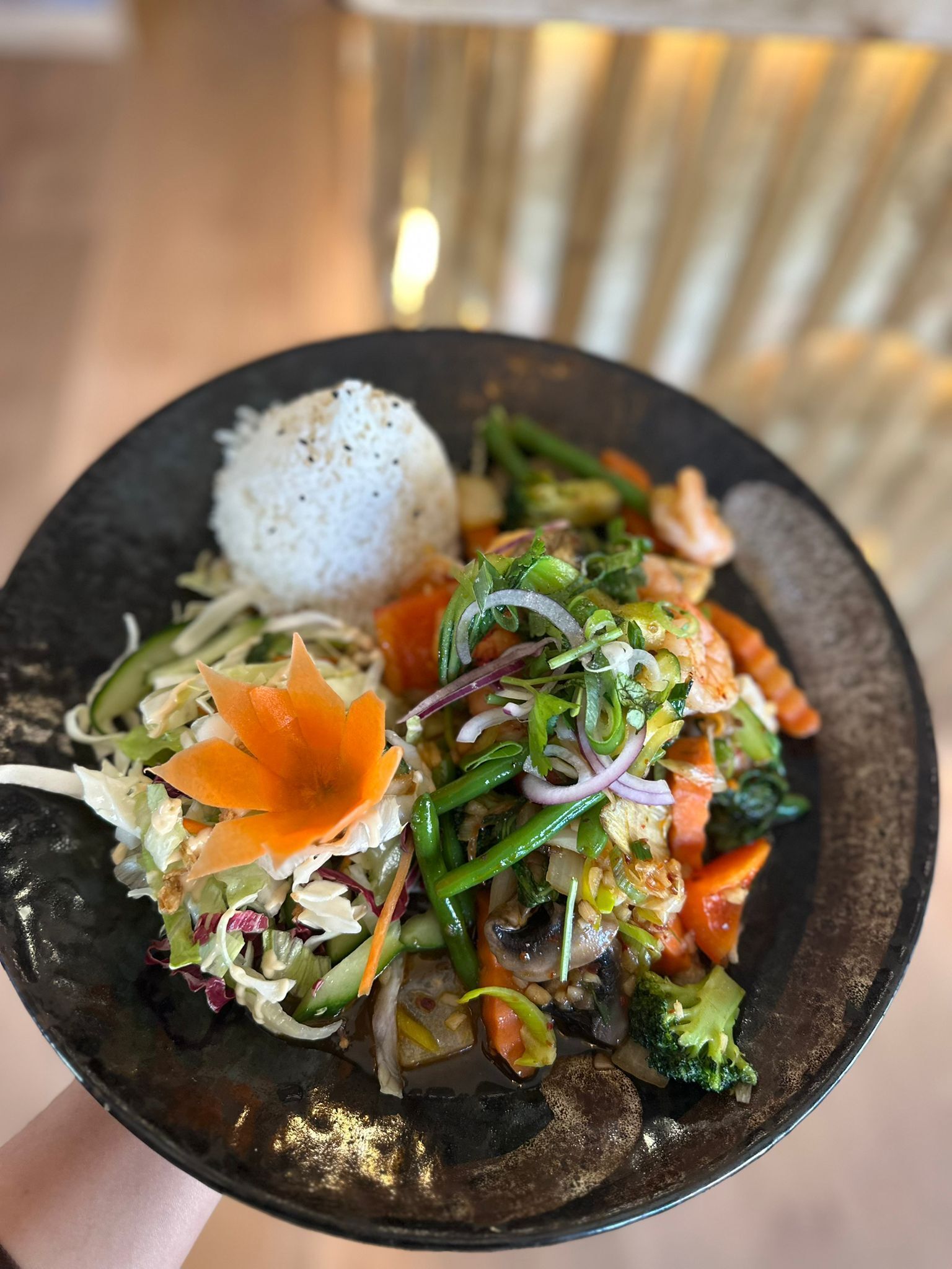 Une assiette de nourriture comprenant du riz, des légumes et un élément décoratif.