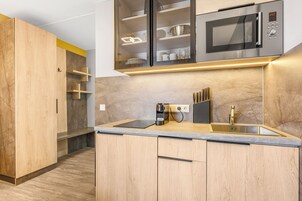 A modern kitchen with wooden cabinets, a built-in microwave, and a coffee maker.