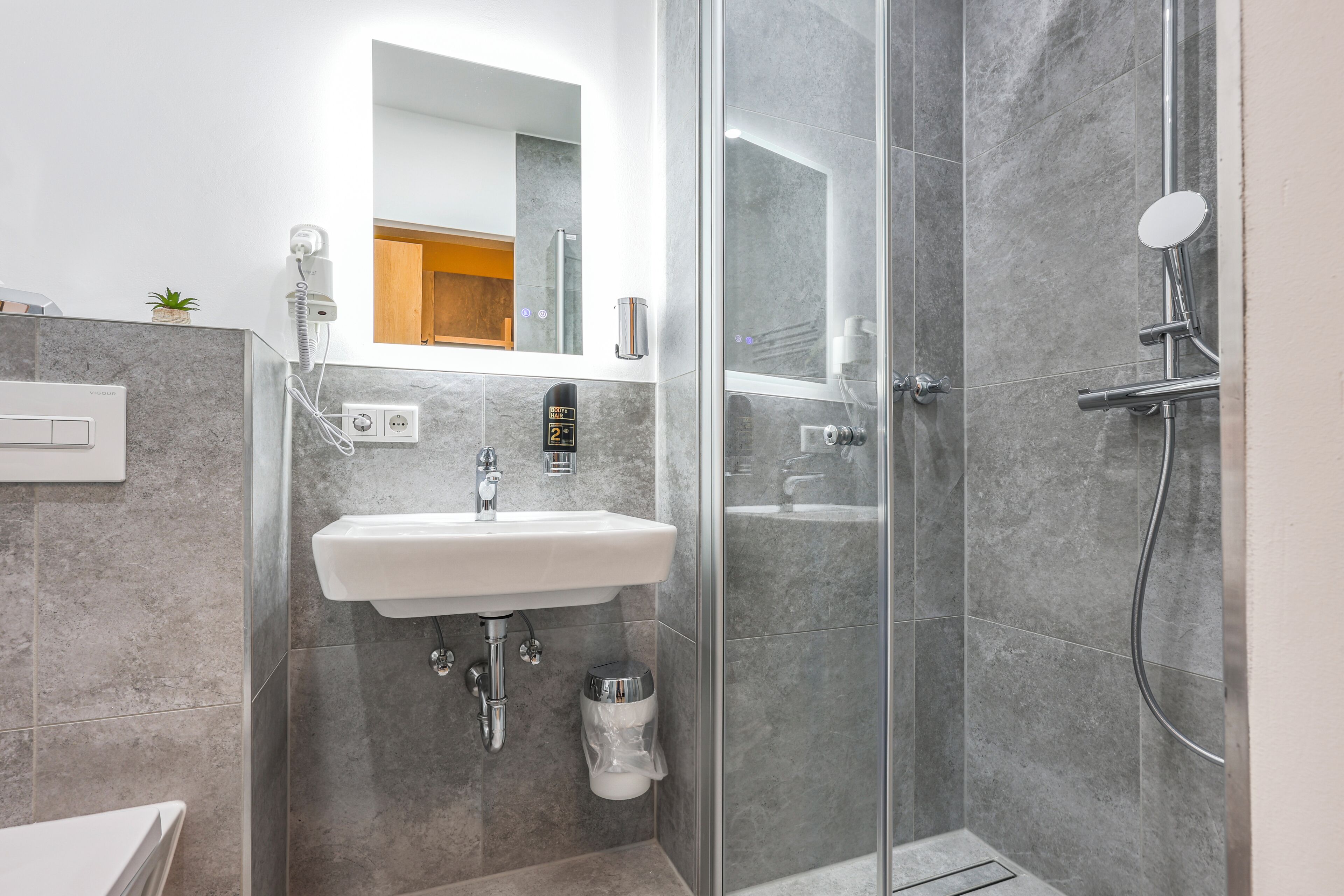 A modern bathroom with a glass-enclosed shower, a white sink, and a mirror above the sink.