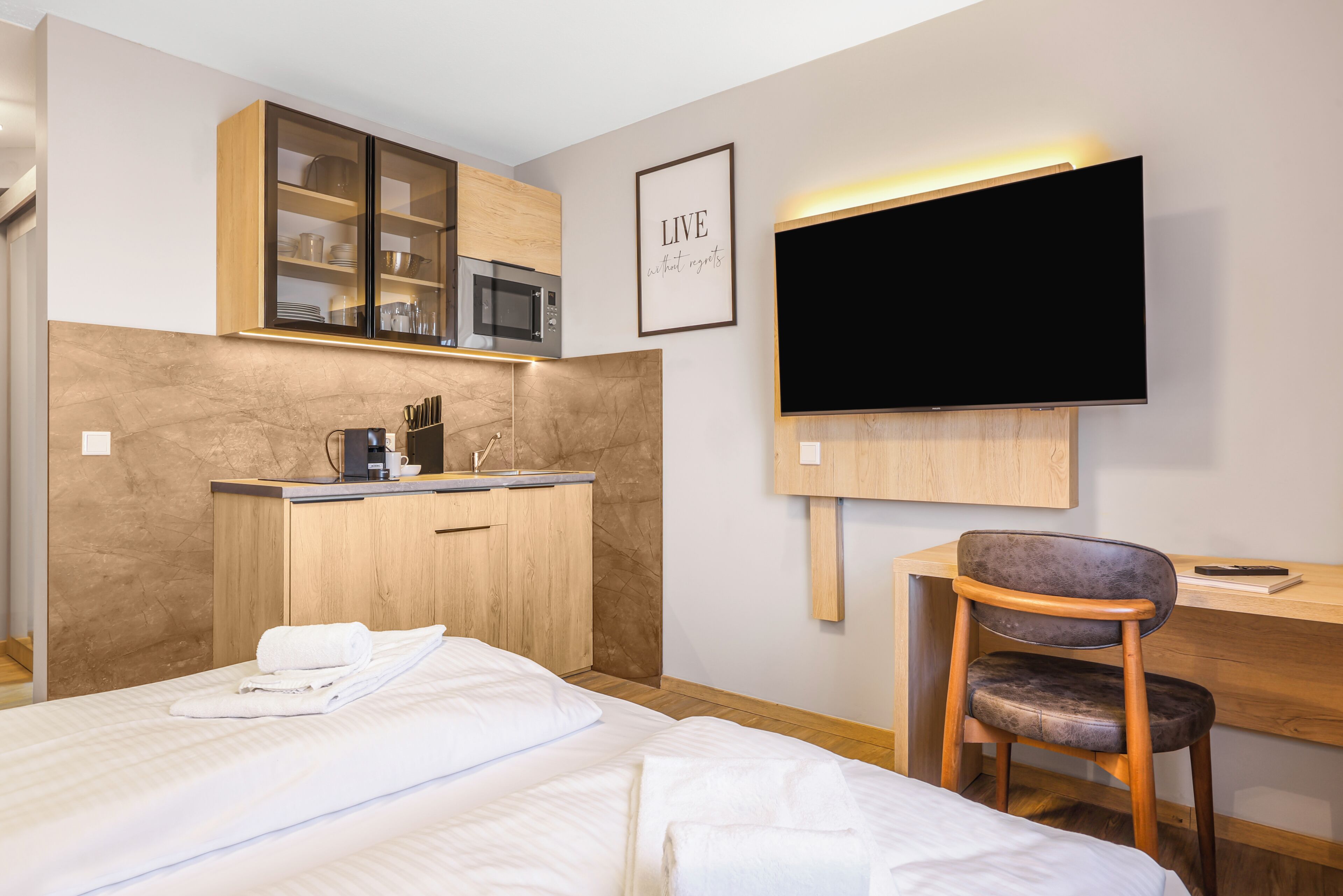 Une chambre d’hôtel équipée d’un lit, d’un bureau, d’une chaise, d’une télévision, d’un four à micro-ondes et d’un meuble avec des portes en verre.