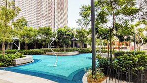 A swimming pool surrounded by greenery and tall buildings in the background. - Massive KL View at M-Vertica by HCK (Kuala Lumpur)
