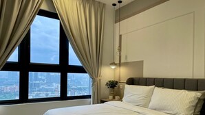 A bedroom with a large window, a bed, a bedside table with a lamp, and a view of a cityscape. - Massive KL View at M-Vertica by HCK (Kuala Lumpur)