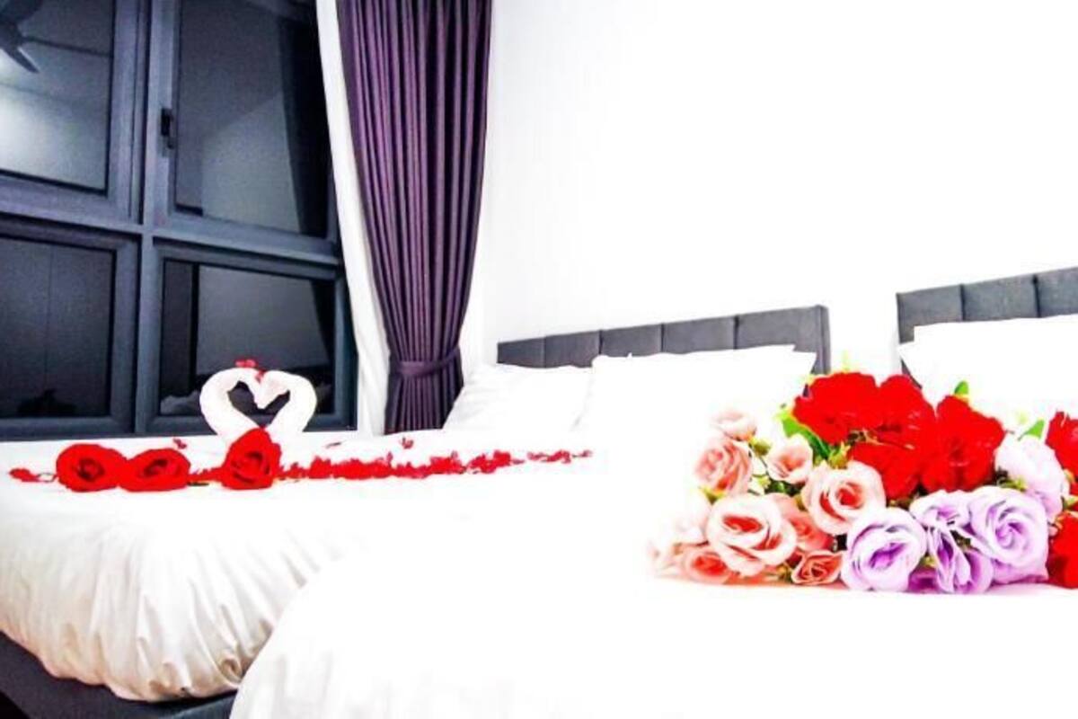 Ein Hotelzimmer mit einem Bett, einem Fenster mit Vorhängen und einem Blumenstrauß auf dem Bett.