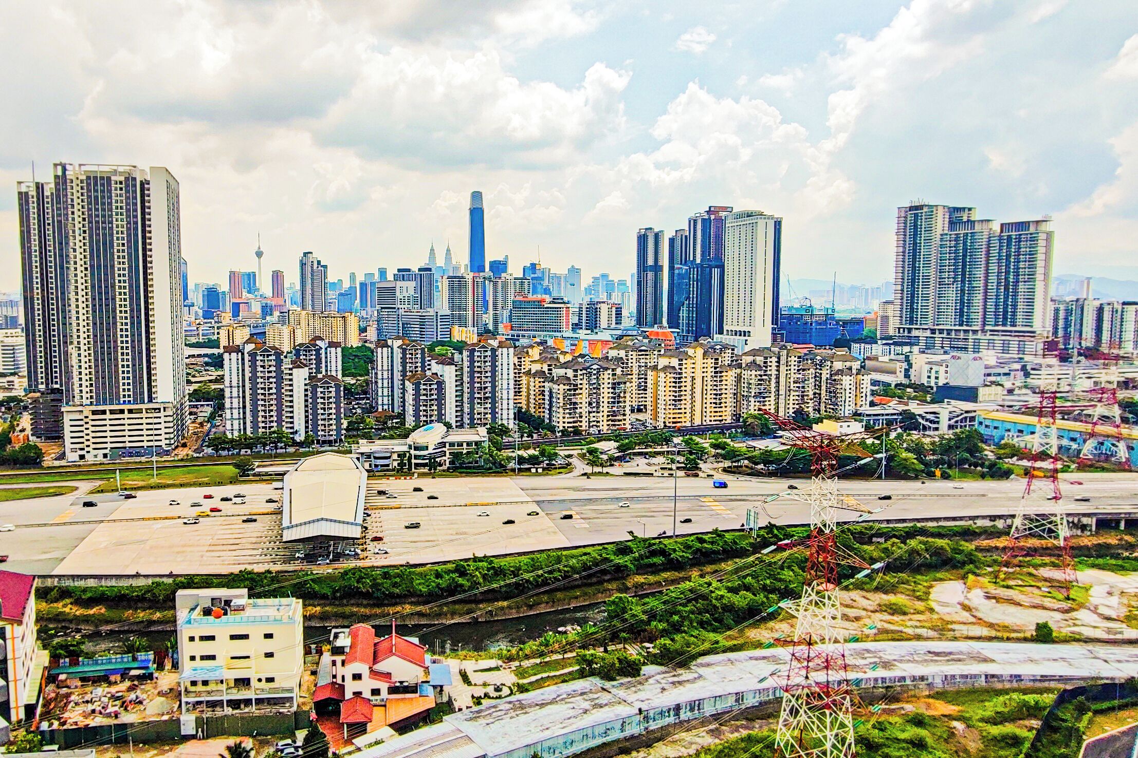 A cityscape with high-rise buildings, a large open plaza, and a train track.