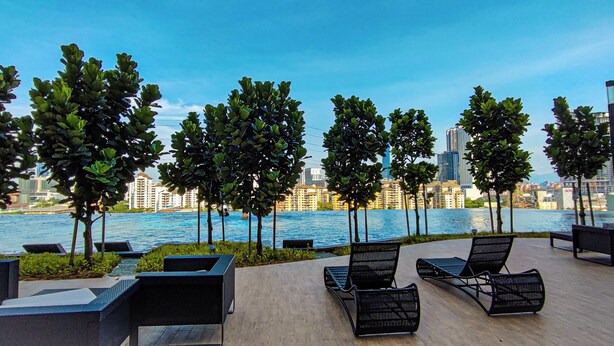 A waterfront patio with lounge chairs and a view of the city skyline. - Massive KL View at M-Vertica by HCK (Kuala Lumpur)