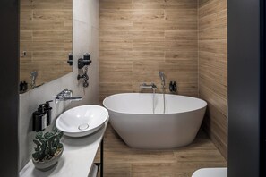 A modern bathroom with a freestanding bathtub, a sink, and a mirror. - Dream Suites (Kraków)