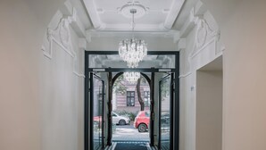 A hallway with a chandelier, double doors, and a checkered floor. - Dream Suites (Kraków)