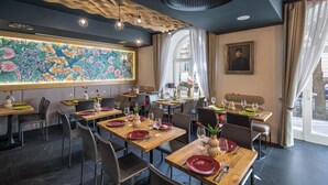 A restaurant interior with multiple dining tables, chairs, and a large floral mural on the wall. - Dream Suites (Kraków)