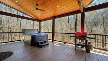 Una terraza techada con jacuzzi, parrilla y techo de madera.