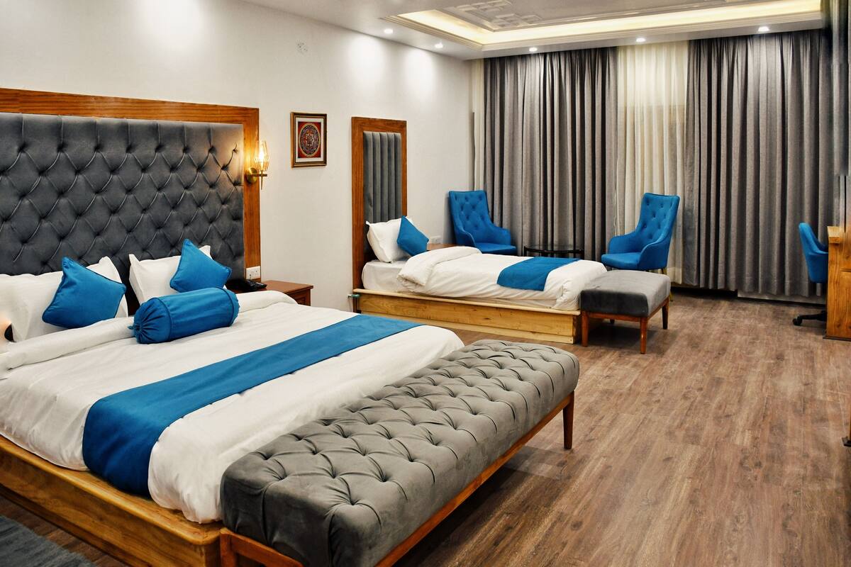 A hotel room with two beds, a bench, and a desk.