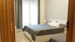 Une chambre à coucher avec un lit, une table de chevet, une lampe et une fenêtre avec des rideaux.