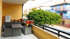 Un balcon doté de meubles en osier, d’une petite table et d’un réfrigérateur.