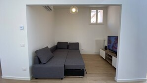 Una sala de estar moderna con un sofá modular, un televisor y un radiador.