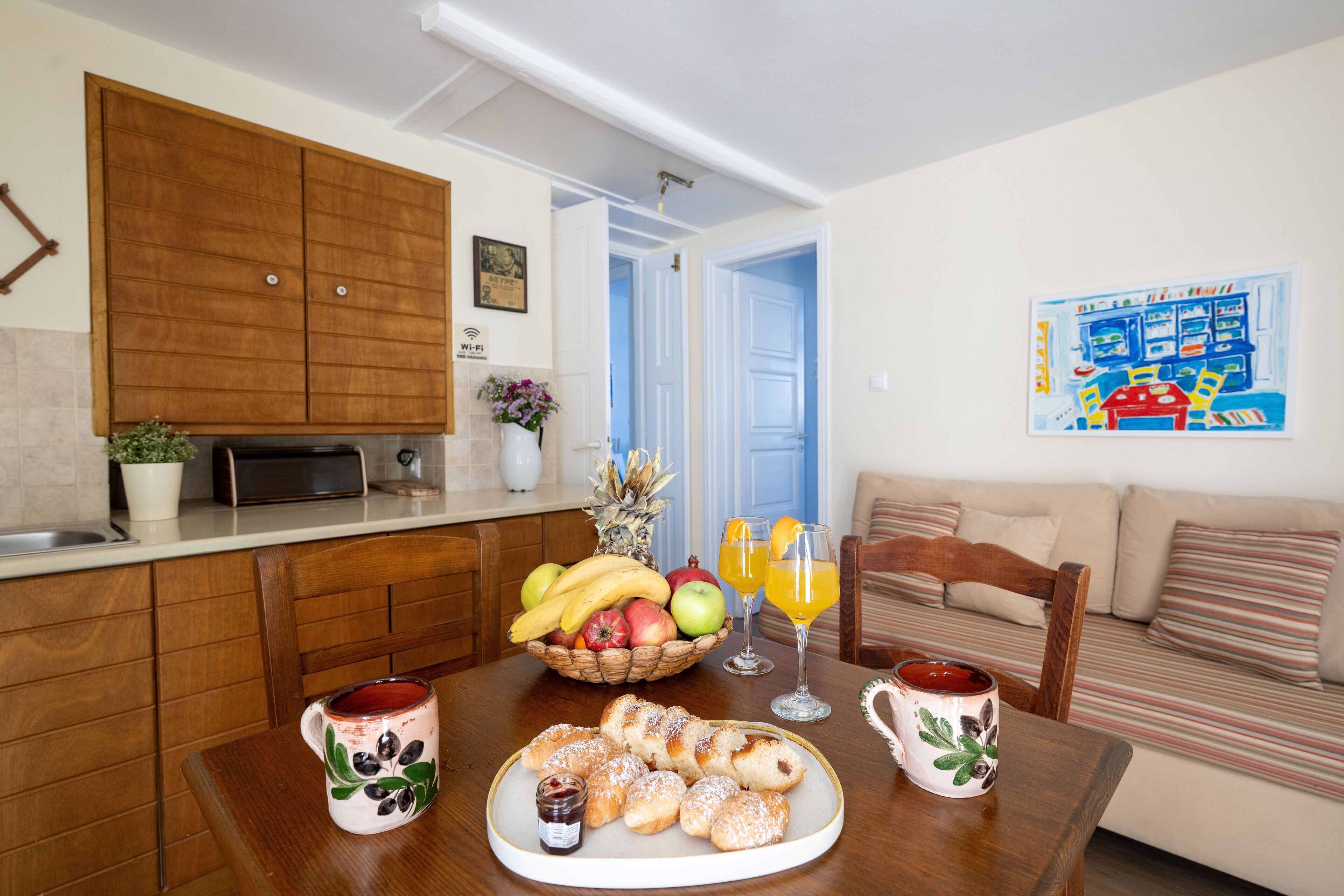 Een ontbijtruimte met een gedekte tafel, inclusief gebak, fruit en drankjes.