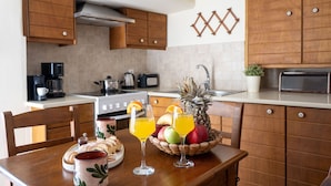 Een keuken met houten kastjes, een fornuis en een ontbijttafel met ontbijtartikelen.