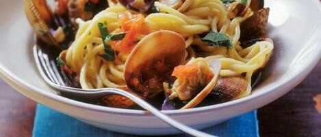 A bowl of pasta with clams and vegetables.