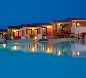 Un hotel con piscina, diversi edifici e illuminazione esterna.