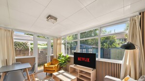 Un salon moderne avec un téléviseur, un canapé, un fauteuil et une plante.