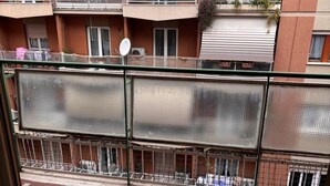 Un immeuble résidentiel doté de nombreux balcons, d’une entrée sécurisée et d’un trottoir pavé.