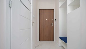 Ein Korridor mit einer Holztür, weißen Wänden und einem weißen Boden.
