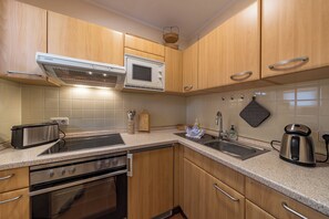 Eine Küche mit Holzschränken, einer Mikrowelle, einem Toaster, einem Spülbecken und einem Wasserkocher.