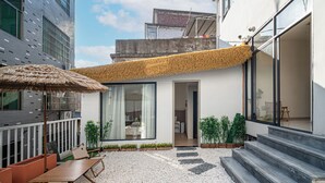 A modern building with a balcony, a thatched roof, and a gravel courtyard. - Jingdezhen Ruchu Hostel - Tao Xichuan  (Jingdezhen)