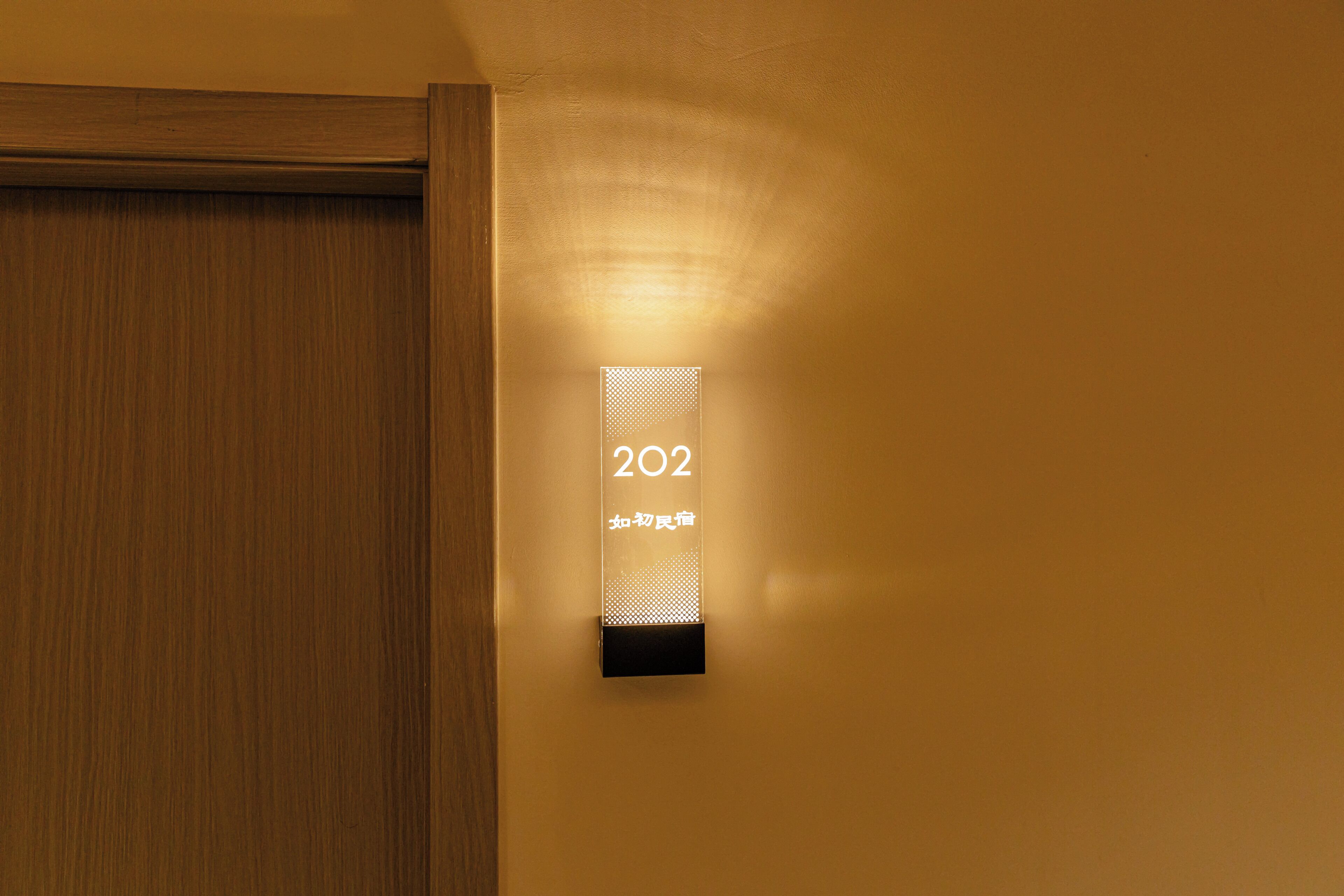 A wall-mounted light fixture with the number '202' and some text in a foreign language.