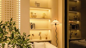 A room with a white sofa, shelves with decorative items, and a plant. - Jingdezhen Ruchu Hostel - Tao Xichuan  (Jingdezhen)