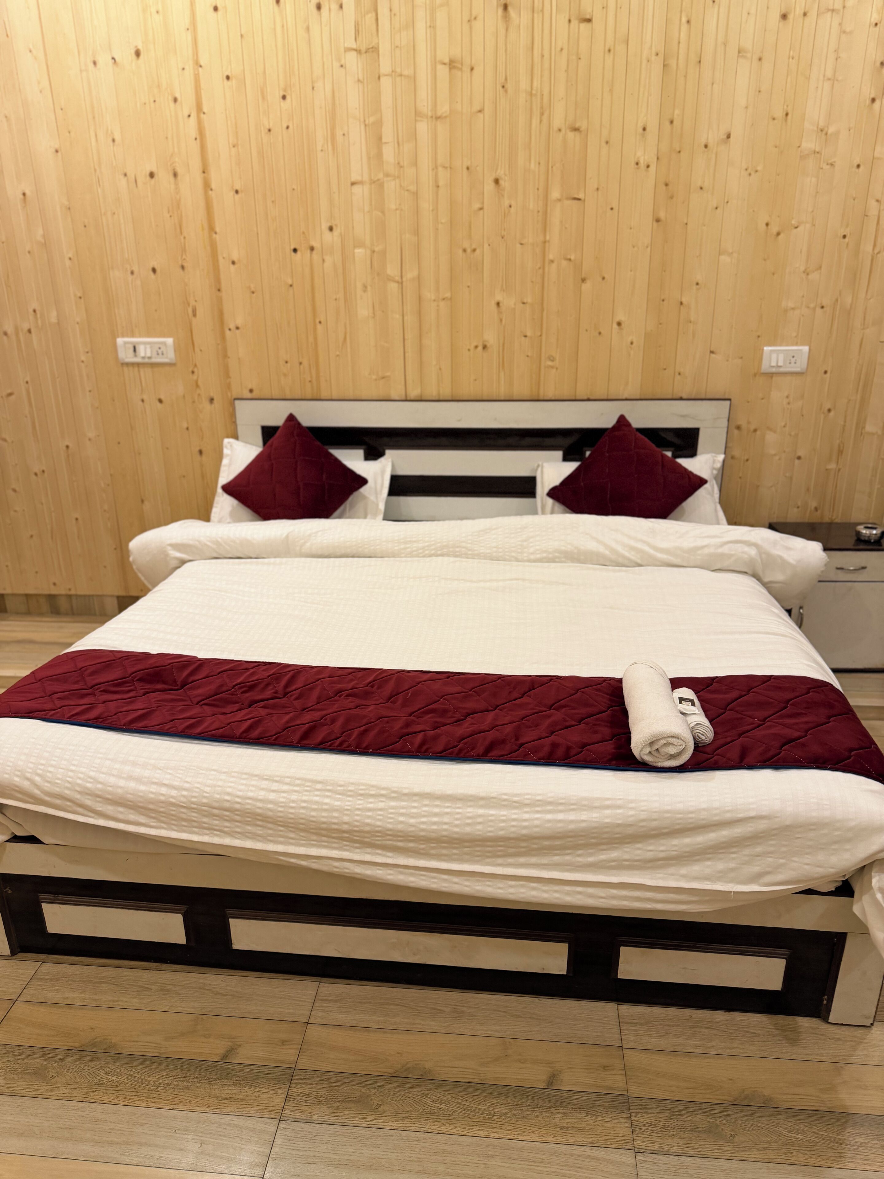 Un lit avec un matelas blanc, une couette rouge et deux oreillers rouges.