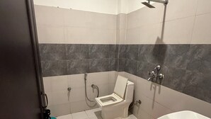 Casa de banho com sanita, chuveiro e lavatório.