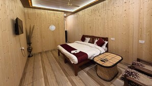 Quarto com painéis de madeira, uma cama, mesa de cabeceira e ventilador de teto.