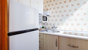 Uma cozinha com geladeira branca, micro-ondas, pia e armários de madeira.