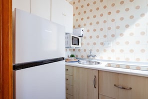 A kitchen with a white refrigerator, a microwave, a sink, and wooden cabinets.