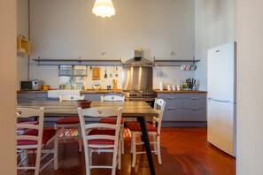 Une cuisine compacte comprenant un coin repas, une hotte en acier inoxydable et un réfrigérateur.