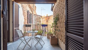 An outdoor patio with a table and chairs, a wooden door, and a brick wall.