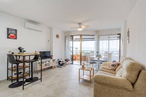 A modern living room with a sofa, TV, and dining area. - Relax Tropical Almuñecar (Almuñécar)